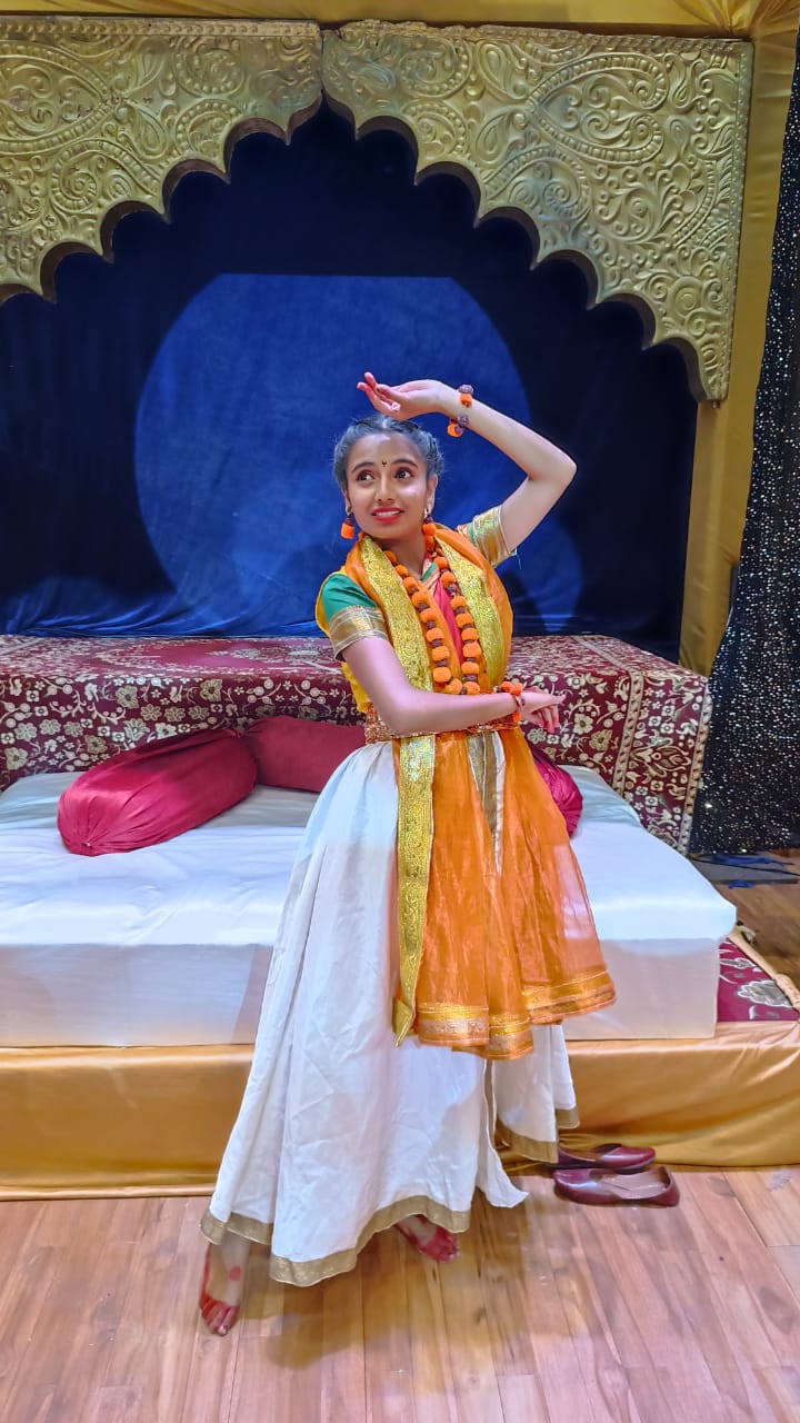 Yashaswee in white/orange costume performing live solo